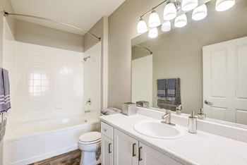 A white bathroom with a toilet, sink, and tub.